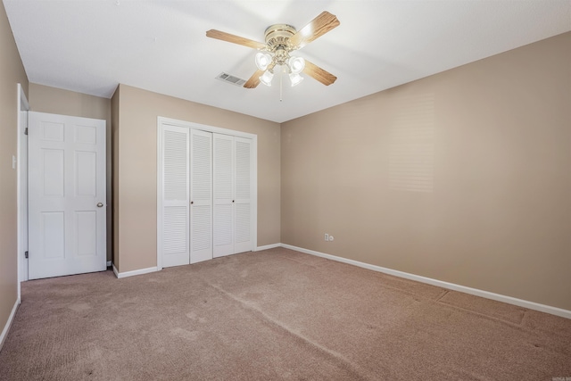 unfurnished bedroom featuring visible vents, a closet, carpet flooring, baseboards, and ceiling fan