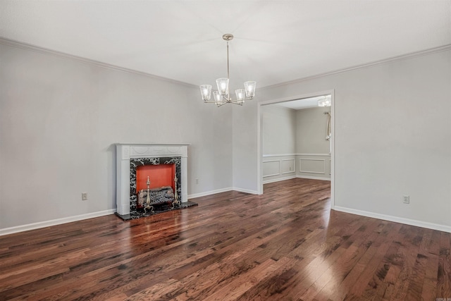 unfurnished living room with ornamental molding, wood finished floors, a fireplace, a decorative wall, and a chandelier