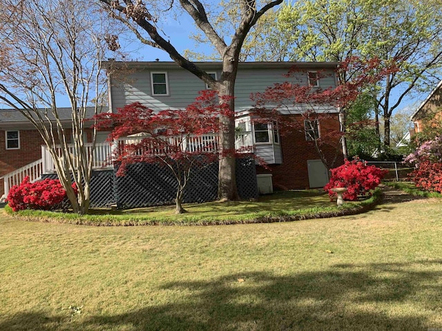 rear view of property featuring a yard, brick siding, and a wooden deck