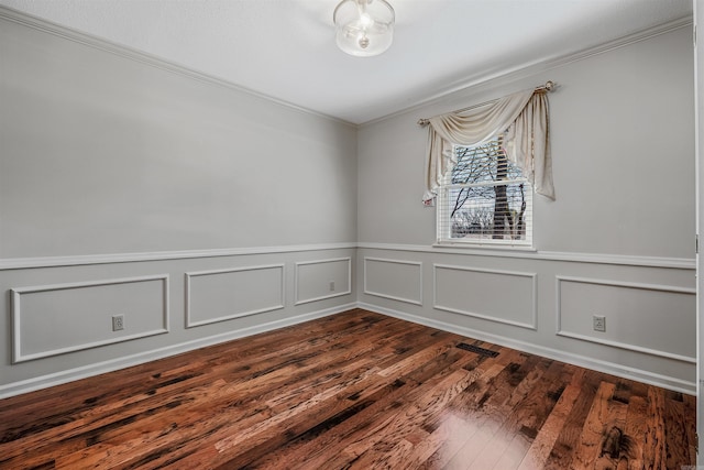 unfurnished room with dark wood-type flooring, a wainscoted wall, and ornamental molding