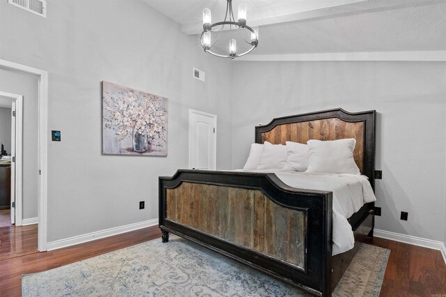 bedroom with a chandelier, visible vents, baseboards, and wood finished floors