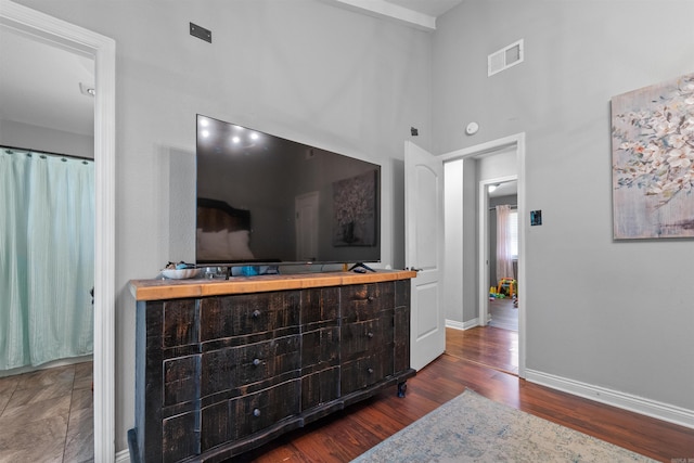 interior space featuring visible vents, baseboards, wood finished floors, and a towering ceiling