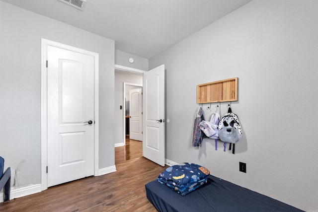 bedroom with visible vents, baseboards, and wood finished floors