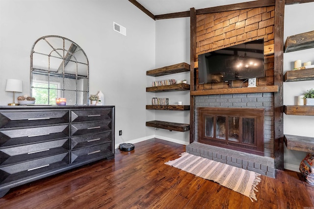 living area with wood finished floors, visible vents, baseboards, crown molding, and a brick fireplace