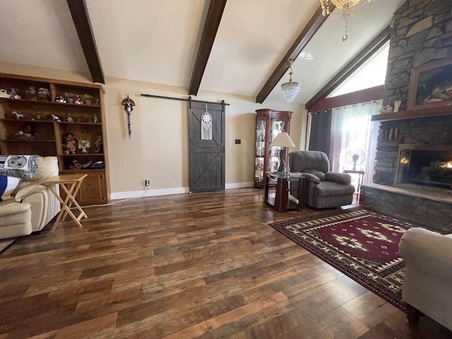 living room with beamed ceiling, a fireplace, a barn door, and wood finished floors