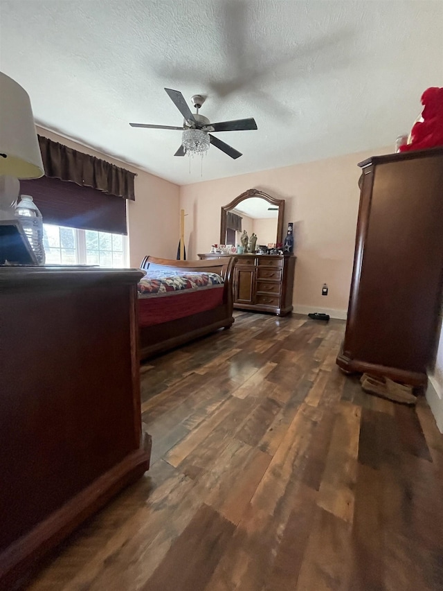 bedroom featuring dark wood-type flooring, a ceiling fan, baseboards, and a textured ceiling