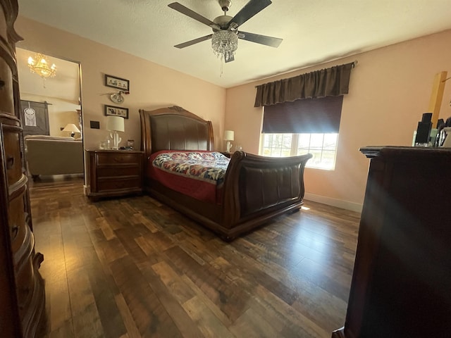 bedroom featuring dark wood-type flooring, ceiling fan with notable chandelier, and baseboards