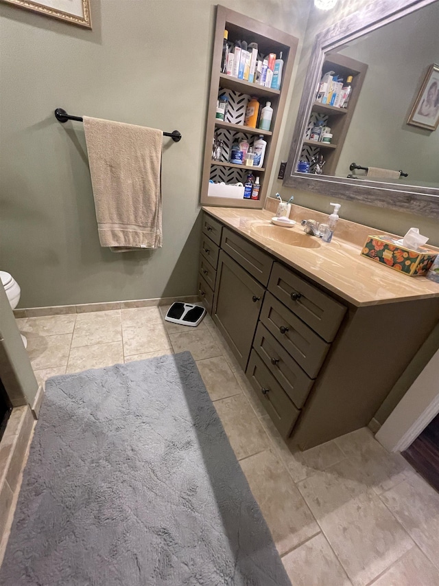 bathroom with vanity, toilet, baseboards, and tile patterned flooring