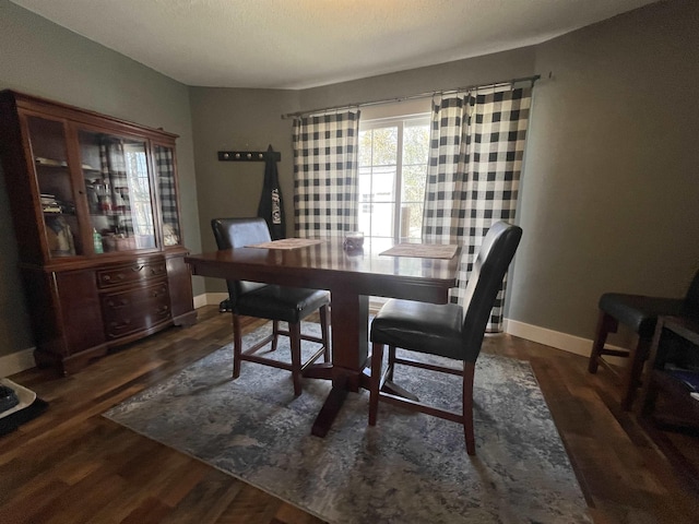 dining space with baseboards and wood finished floors