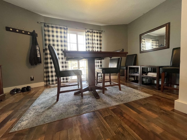 dining space with baseboards and wood finished floors