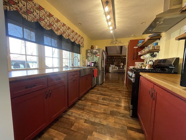 kitchen with dark wood-type flooring, wall chimney range hood, appliances with stainless steel finishes, a textured ceiling, and open shelves