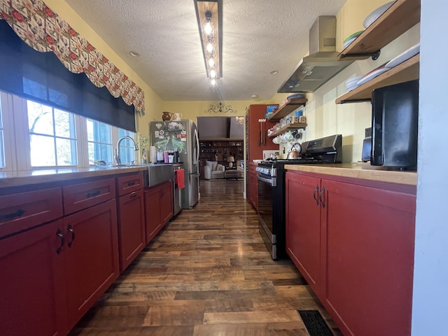 kitchen with open shelves, dark wood-style flooring, stainless steel appliances, a textured ceiling, and wall chimney range hood