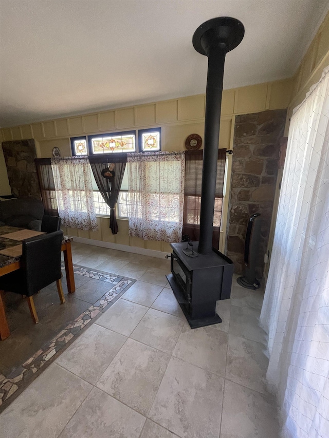 living area with a wood stove, light tile patterned flooring, and baseboards