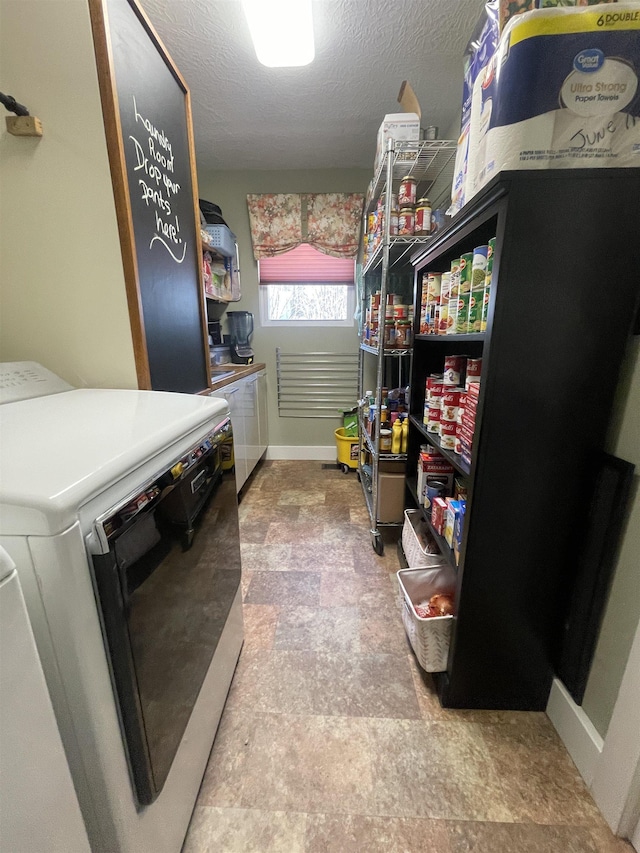 washroom featuring baseboards, laundry area, stone finish flooring, a textured ceiling, and washer and clothes dryer