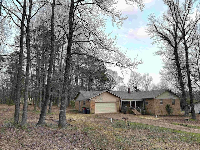 view of front of house featuring brick siding, an attached garage, and a chimney