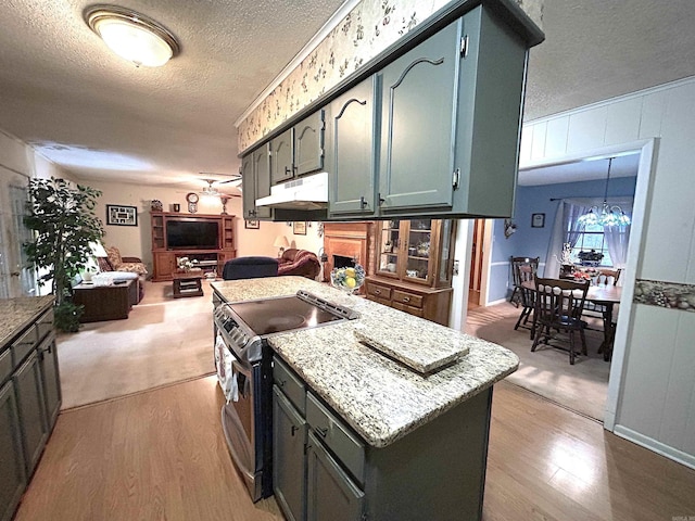 kitchen featuring light wood-type flooring, electric range, a textured ceiling, and open floor plan