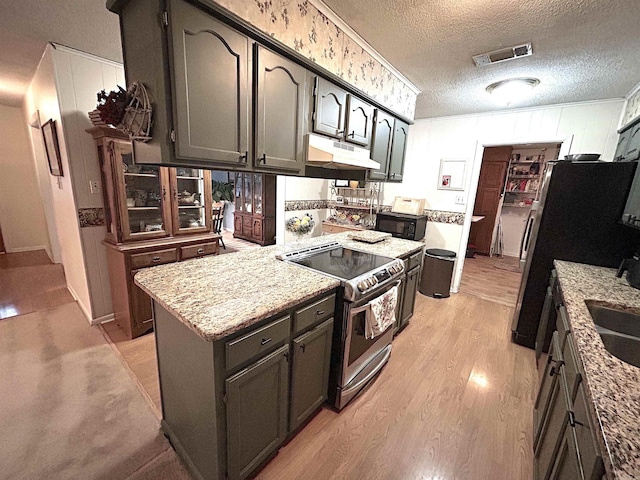 kitchen with visible vents, under cabinet range hood, light wood-type flooring, stainless steel range with electric stovetop, and a textured ceiling