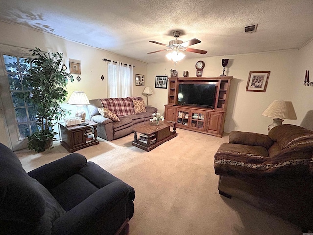 living area featuring ceiling fan, a textured ceiling, visible vents, and light carpet