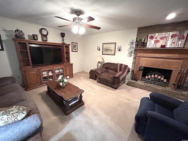 living room with a fireplace, a ceiling fan, carpet floors, and a textured ceiling