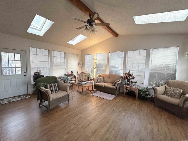 living room with vaulted ceiling with skylight, wood finished floors, and a wealth of natural light