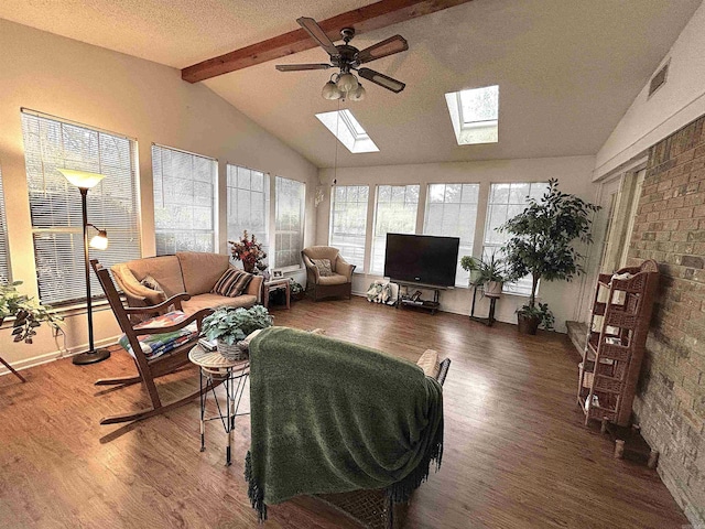 living room featuring lofted ceiling with skylight, wood finished floors, visible vents, and ceiling fan