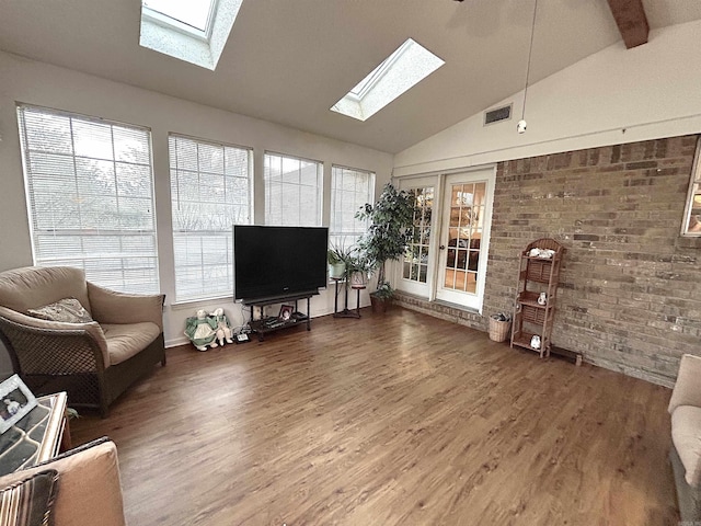 living room featuring a wealth of natural light, visible vents, wood finished floors, and a skylight