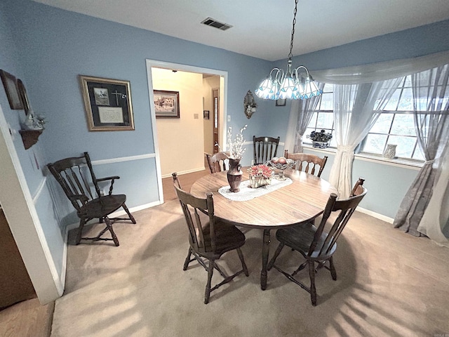 dining room featuring baseboards, visible vents, a chandelier, and light carpet