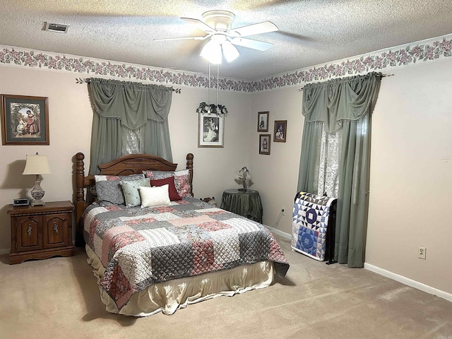 bedroom featuring visible vents, baseboards, light carpet, a textured ceiling, and a ceiling fan