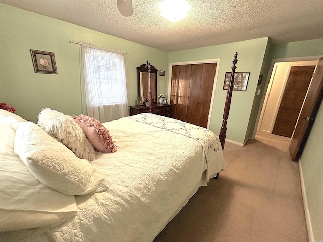 bedroom with baseboards, light colored carpet, a closet, a textured ceiling, and a ceiling fan