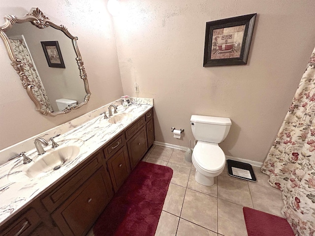 bathroom with a sink, toilet, double vanity, and tile patterned flooring