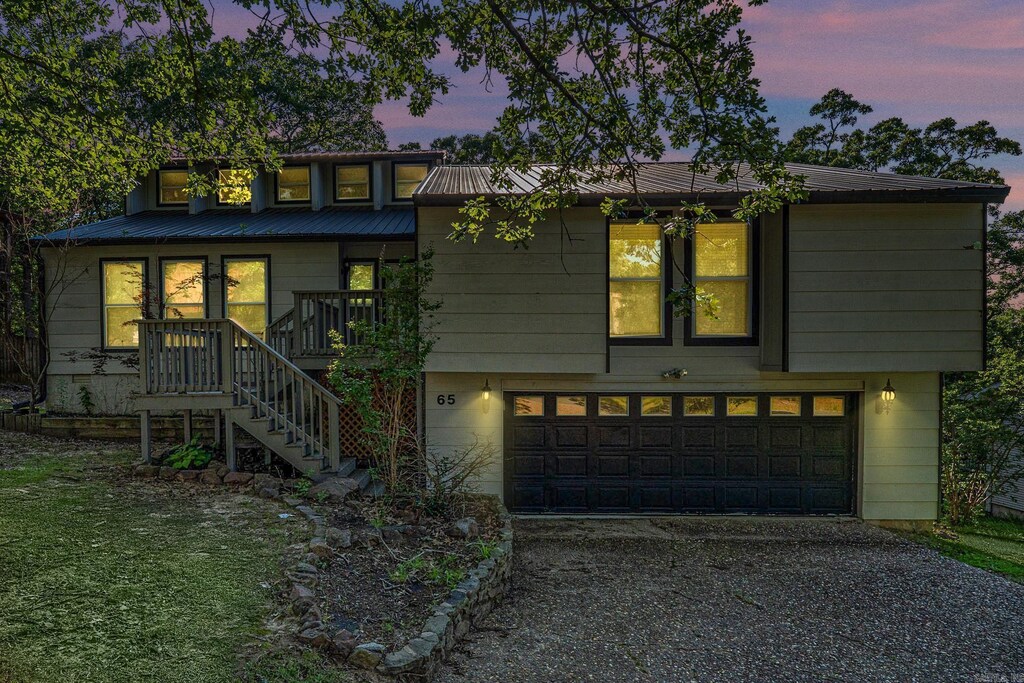 65 Stoneledge Dr, Maumelle, AR 72113 - view of front facade featuring stairs, a garage, metal roof, and driveway