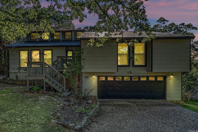 view of front facade featuring stairs, a garage, metal roof, and driveway