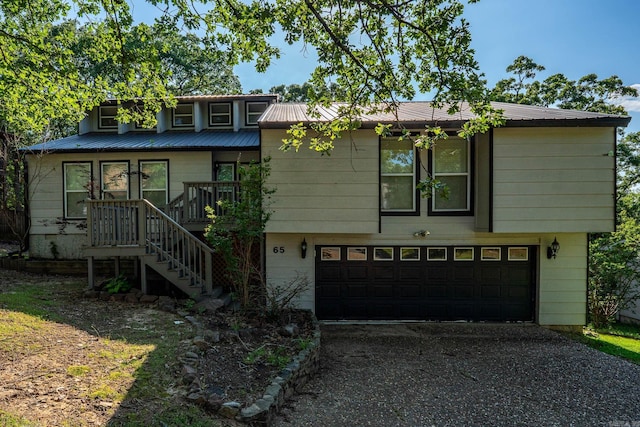 split level home with stairs, an attached garage, driveway, and metal roof