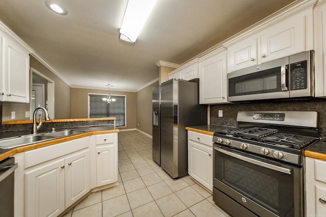 kitchen with a sink, stainless steel appliances, crown molding, light tile patterned floors, and a chandelier