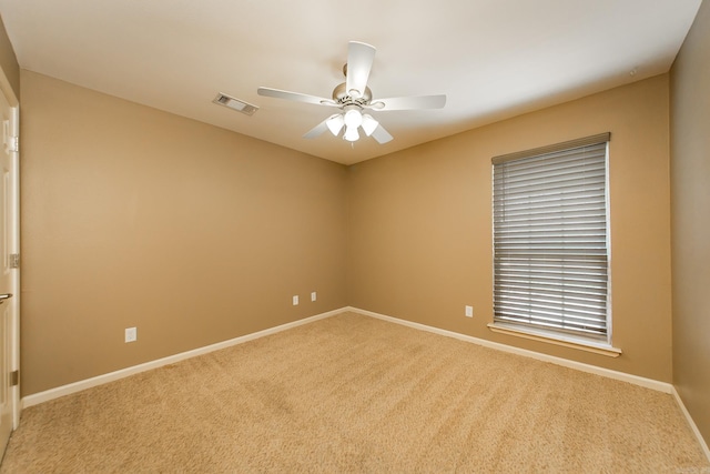 carpeted empty room featuring baseboards, visible vents, and ceiling fan