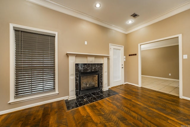 unfurnished living room featuring visible vents, crown molding, baseboards, and wood finished floors