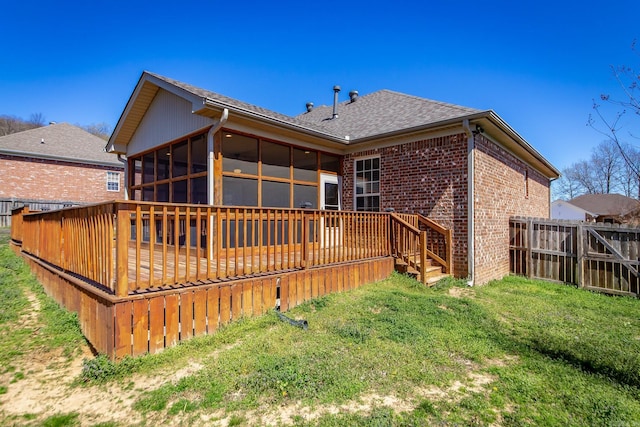 back of house featuring a deck, fence, brick siding, and a sunroom