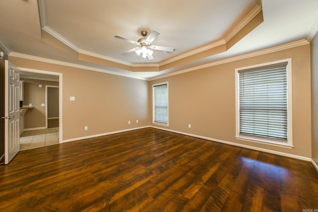 empty room with a raised ceiling, ceiling fan, and wood finished floors