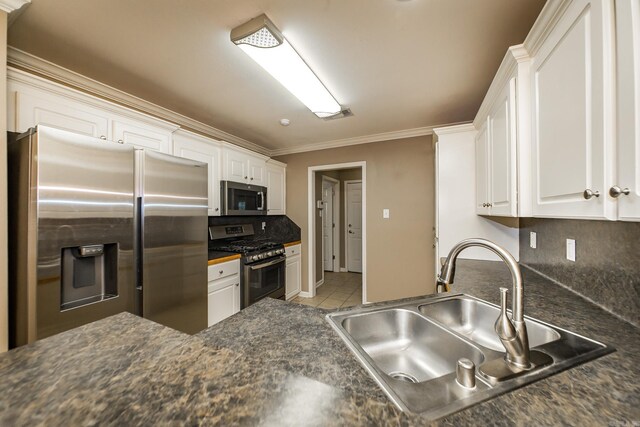 kitchen featuring a sink, stainless steel appliances, dark countertops, and white cabinets