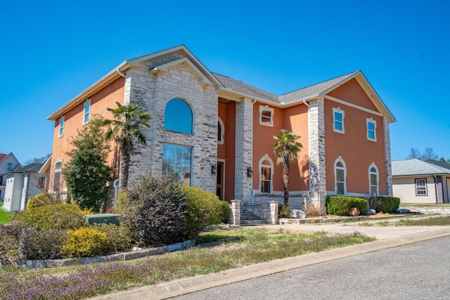 view of front of home featuring stone siding and stucco siding