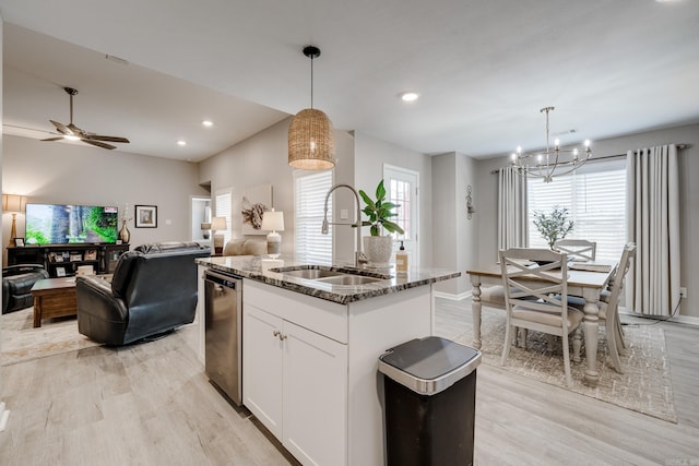 kitchen with light wood-type flooring, a sink, open floor plan, dark stone counters, and dishwasher