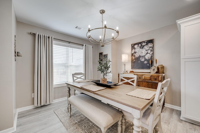 dining space with an inviting chandelier, baseboards, light wood-type flooring, and visible vents