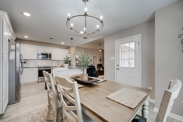 dining area featuring light wood finished floors, recessed lighting, ceiling fan with notable chandelier, and baseboards