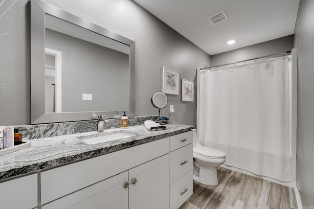 bathroom with visible vents, toilet, wood finished floors, vanity, and shower / bathtub combination with curtain