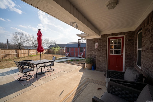 view of patio featuring outdoor dining space, an outdoor structure, a fenced backyard, and a shed