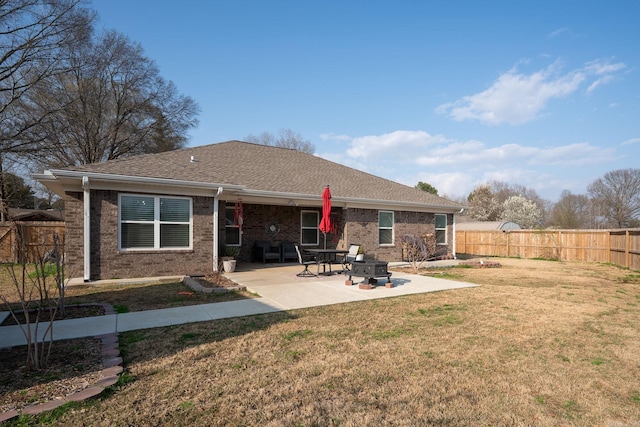 back of house featuring a lawn, a fenced backyard, brick siding, and a patio area