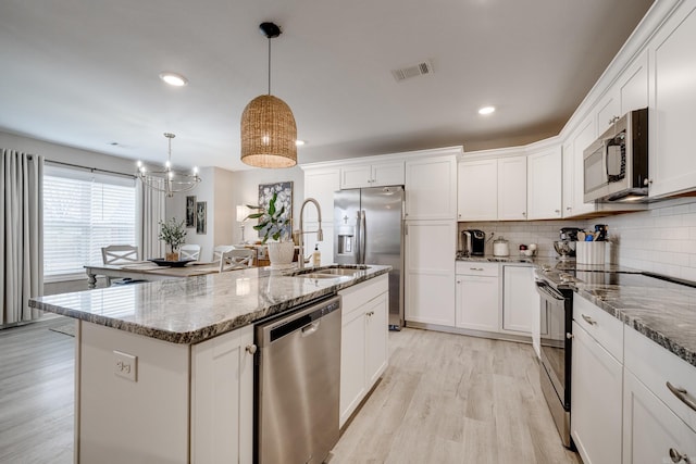 kitchen with light wood-type flooring, visible vents, appliances with stainless steel finishes, white cabinets, and decorative backsplash