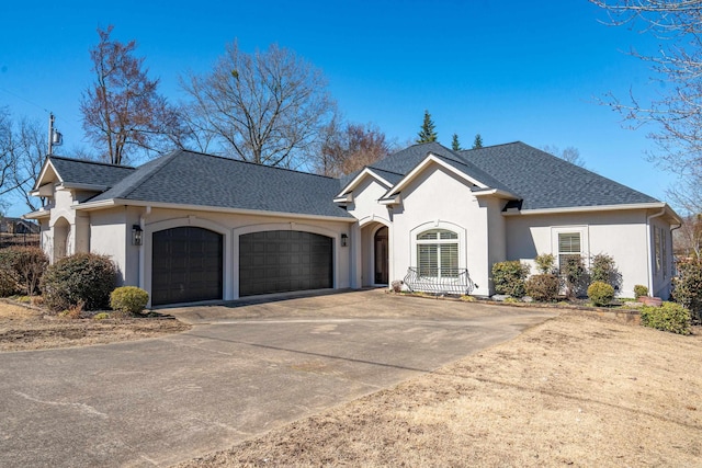 view of front of property featuring stucco siding, roof with shingles, concrete driveway, and an attached garage