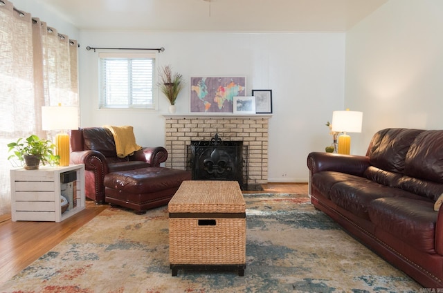 living room with a brick fireplace, wood finished floors, and crown molding