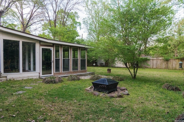 view of yard with an outdoor fire pit, a sunroom, and fence